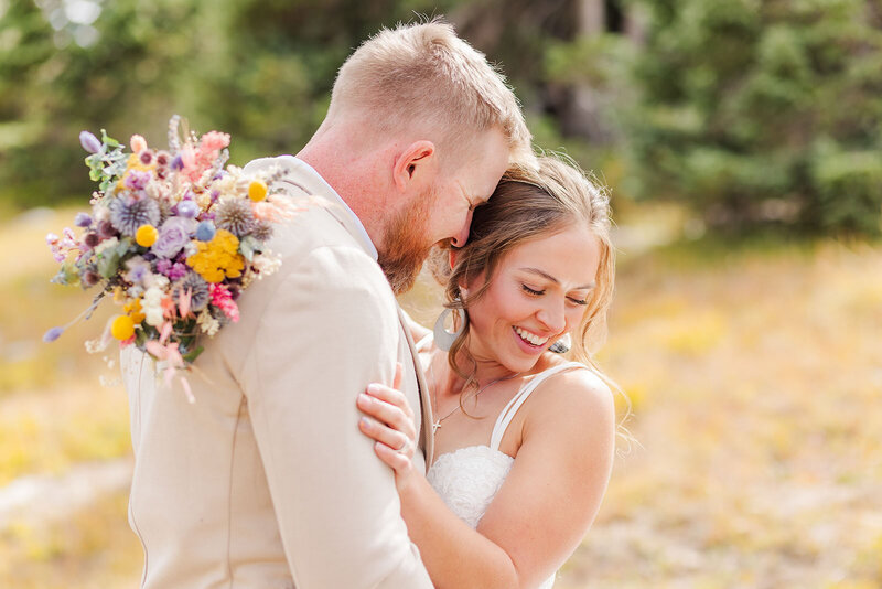 Smiling bride and groom embracing at their intimate elopement at the St. Albans Chapel in the stunning Snowy Range Mountains.