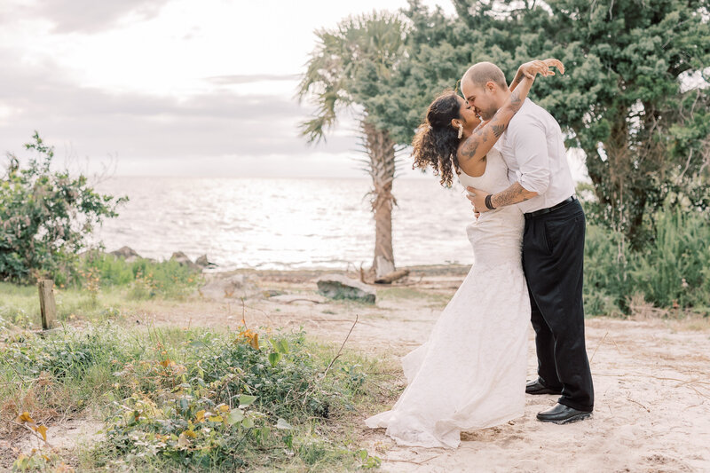 Couple kisses each other during their elopement on a boardwalk surrounded by Florida's tropical foliage.