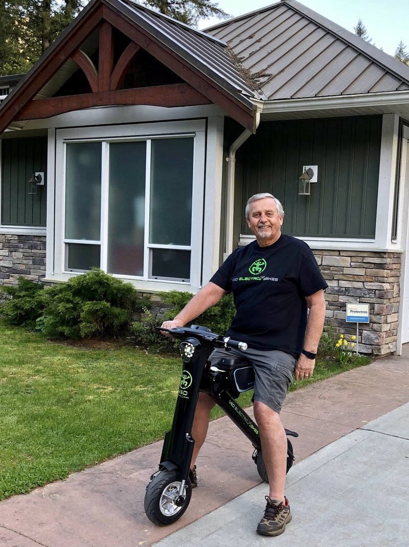 Gentleman sitting on his black Go-Bike M1 in front of his home
