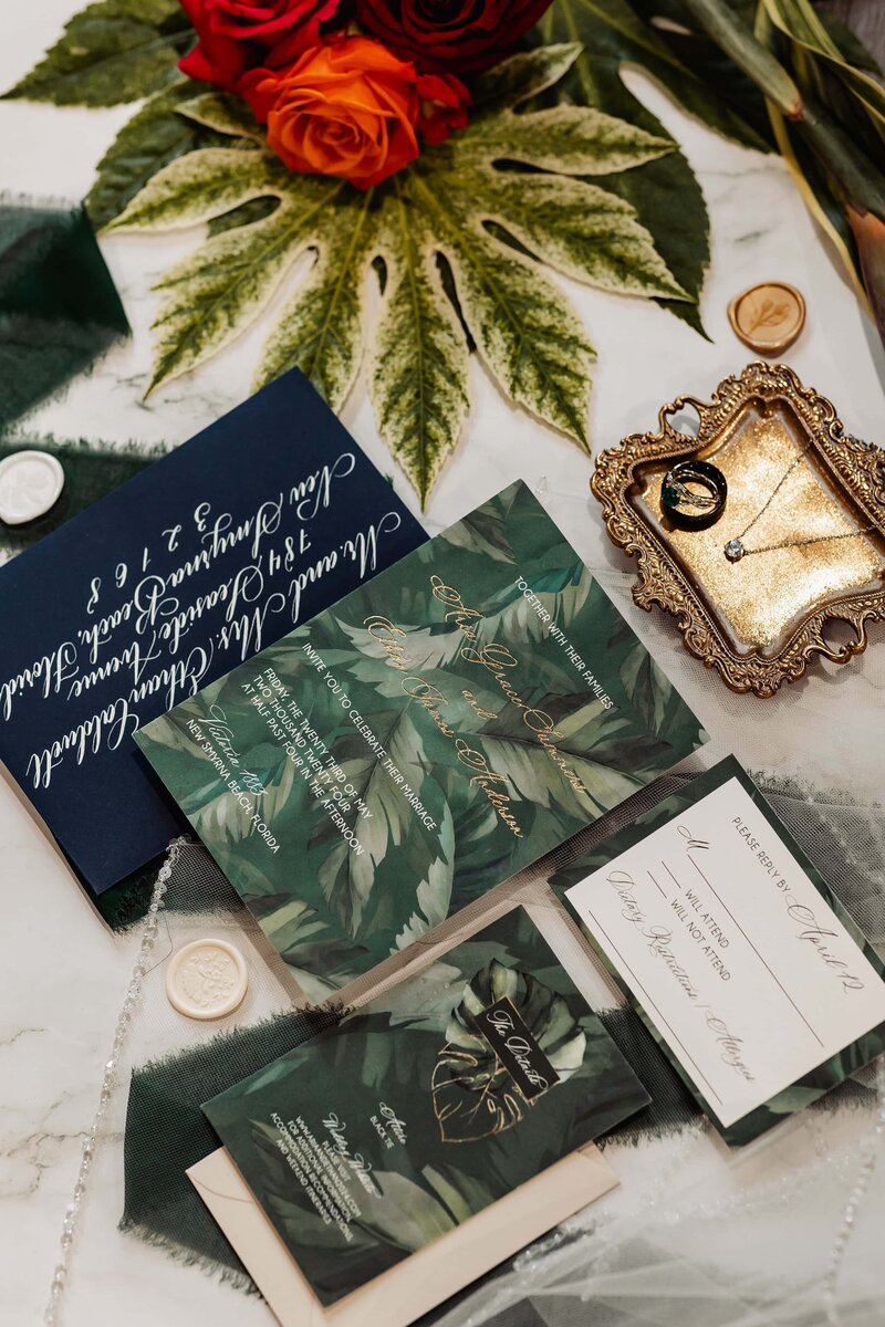 Moody botanical invitation suite with dark green and navy calligraphy.