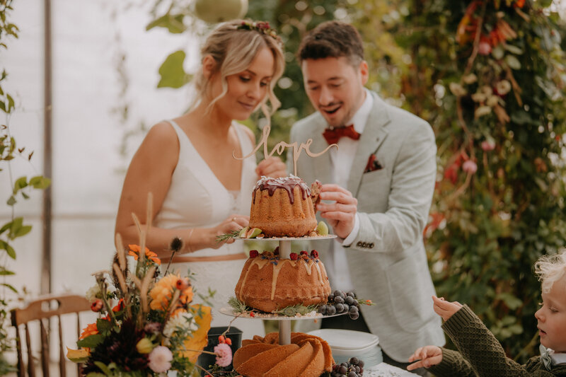 Brautpaar schneidet eine biologische Hochzeitstorte im Glashaus der Location Vom Hügel in der Steiermark an.