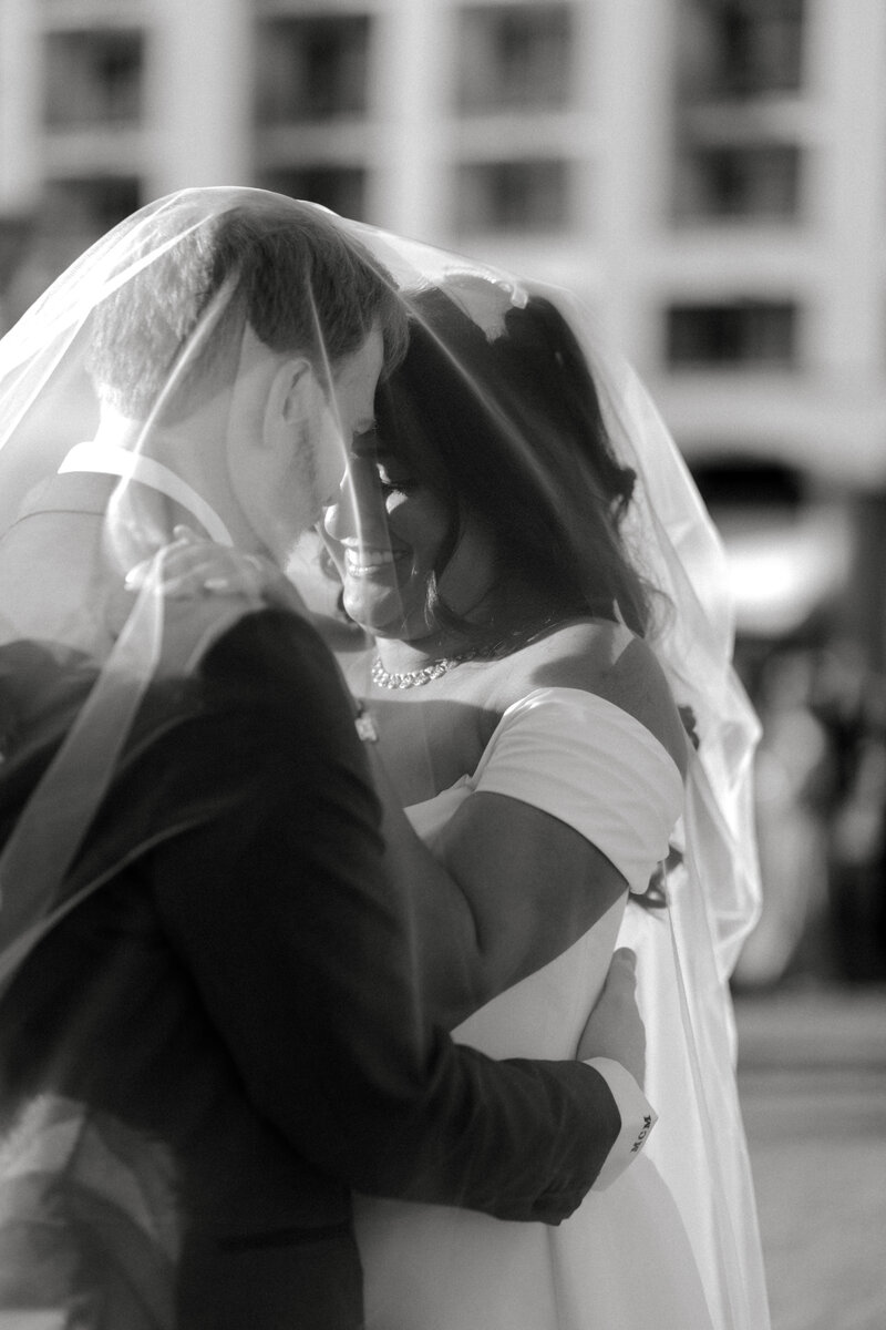 Black-and-white photo of a bride and groom embracing during their wedding, captured by Jacksonville-based wedding videographers, Tyler and Makenzie Films.