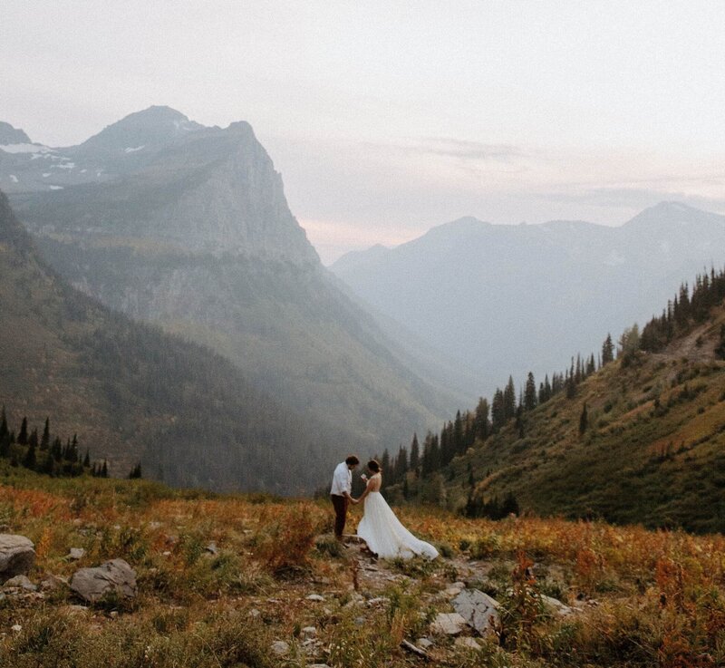 A couple holds hands during their 5-year vow renewal with Colorado elopement photo and video team Alpine Vows, standing in a breathtaking alpine valley surrounded by towering mountain peaks.