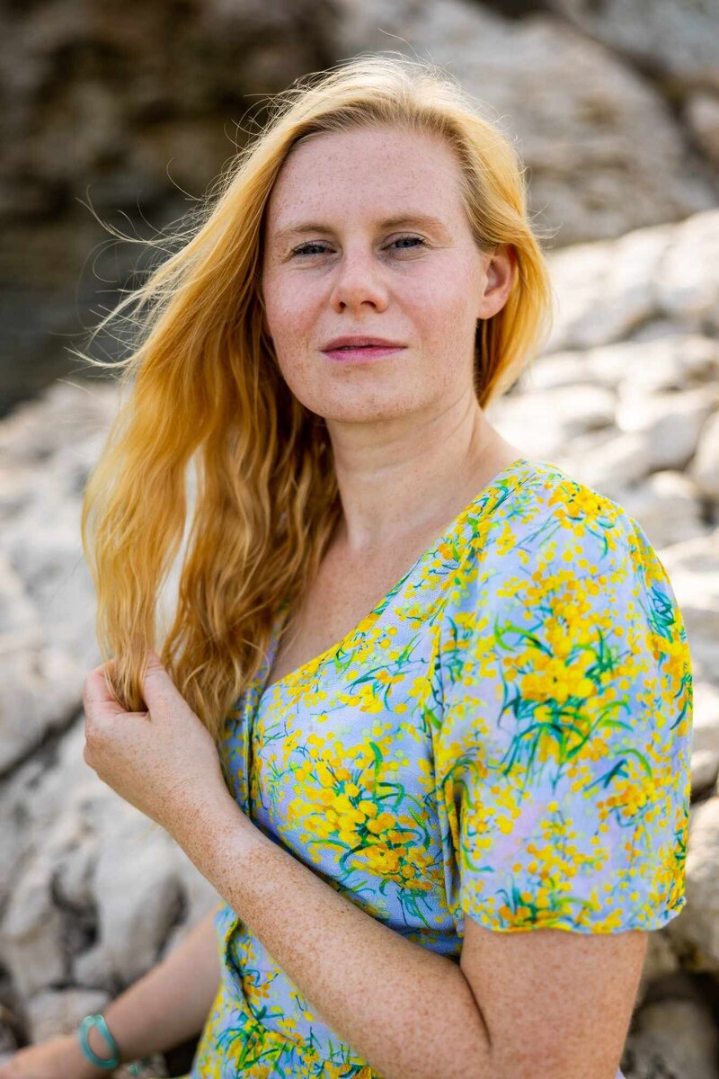 Porträt von Marie-Theres Schwinn, Mentorin im Programm "Embody Your Creativity", die mit einem einladenden Lächeln und einem floralen Kleid auf dem Weg zur emotionalen Freiheit und kreativen Entfaltung ist. Dieses Bild spiegelt ihre Rolle wider, Schauspielerinnen zu unterstützen, ihre innere Kraft zu entdecken, authentisch zu leben und Selbstzweifel zu überwinden, während sie ihre kreative Stimme entfalten