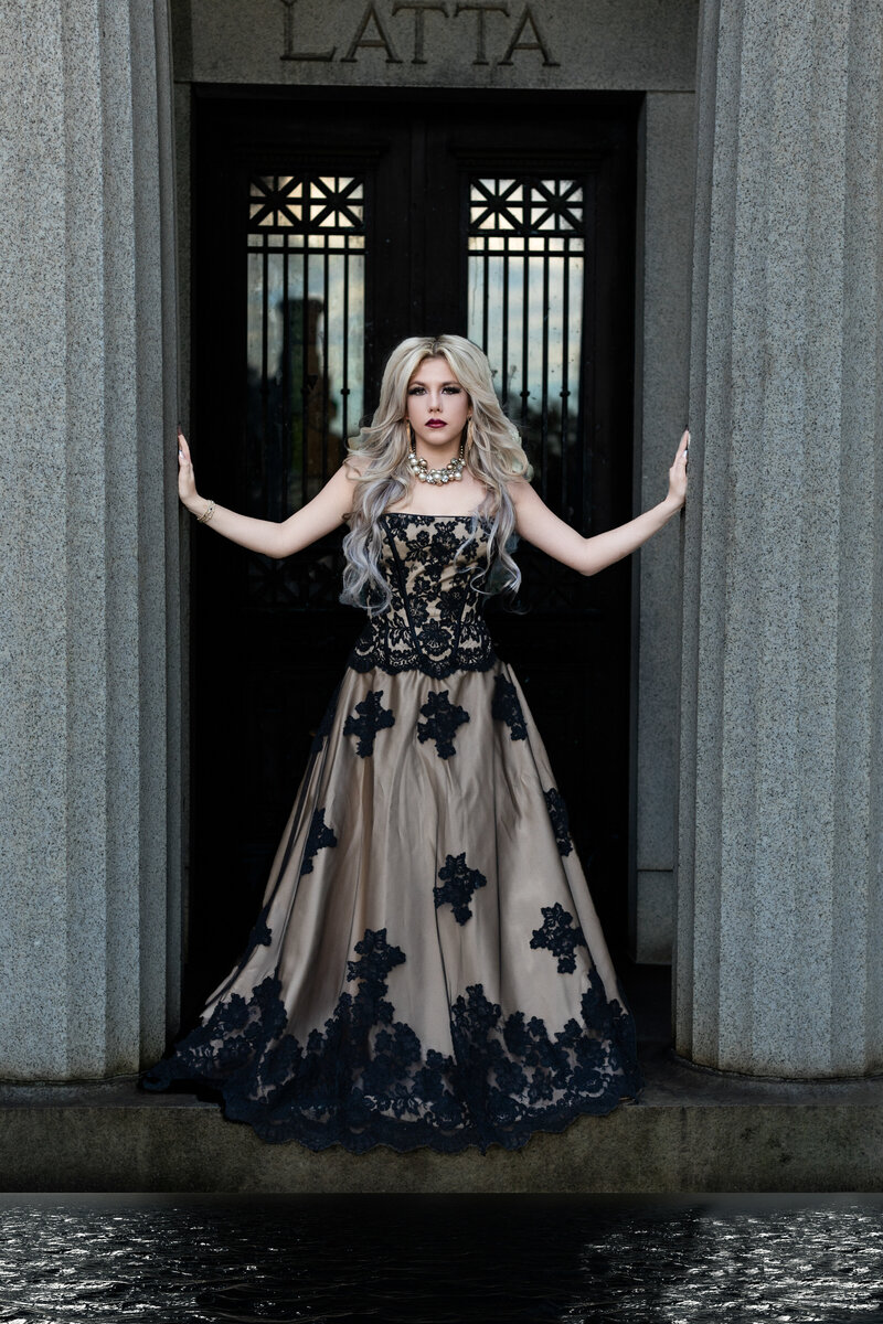 Senior girl who is standing in the doorway of a mausoleum wearing a long gown with the sunset coming through the back windows.  Beautiful lighting! 