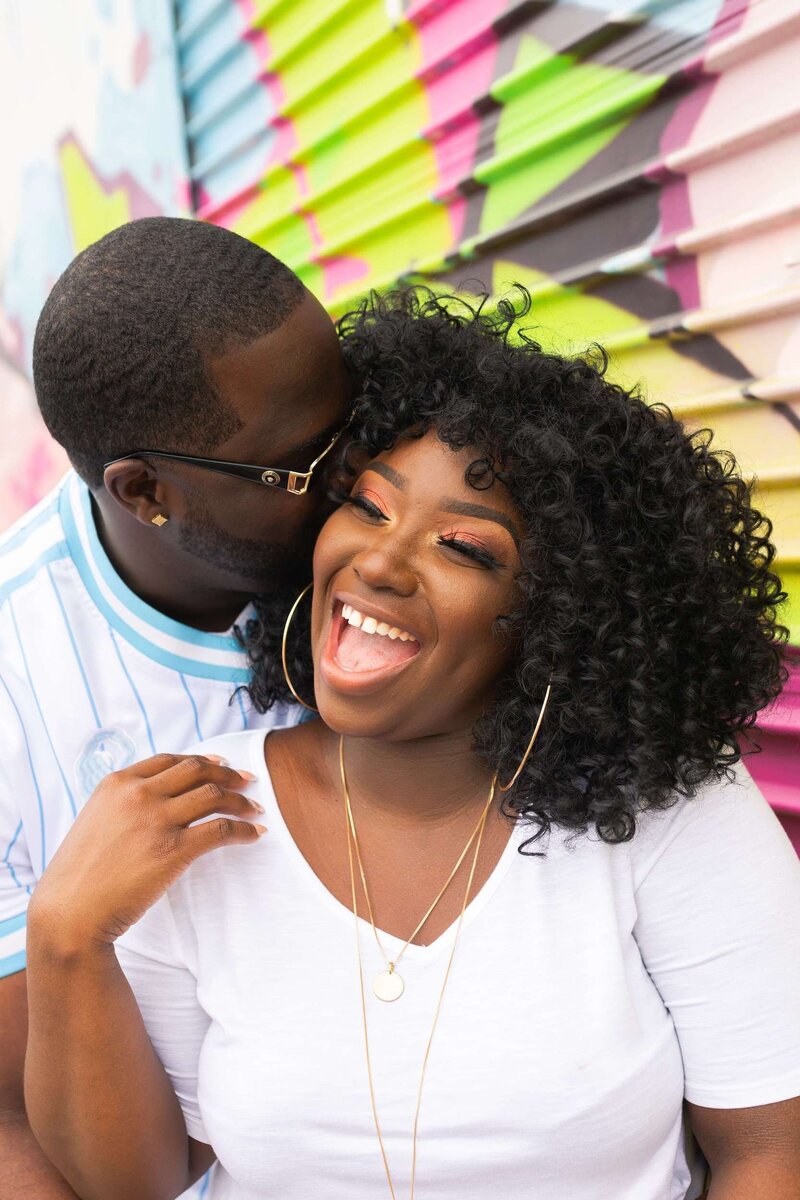 engaged couple laugh during their engagement session groom kisses bride to be on a rooftop in downtown Houston by Swish and Click Photography