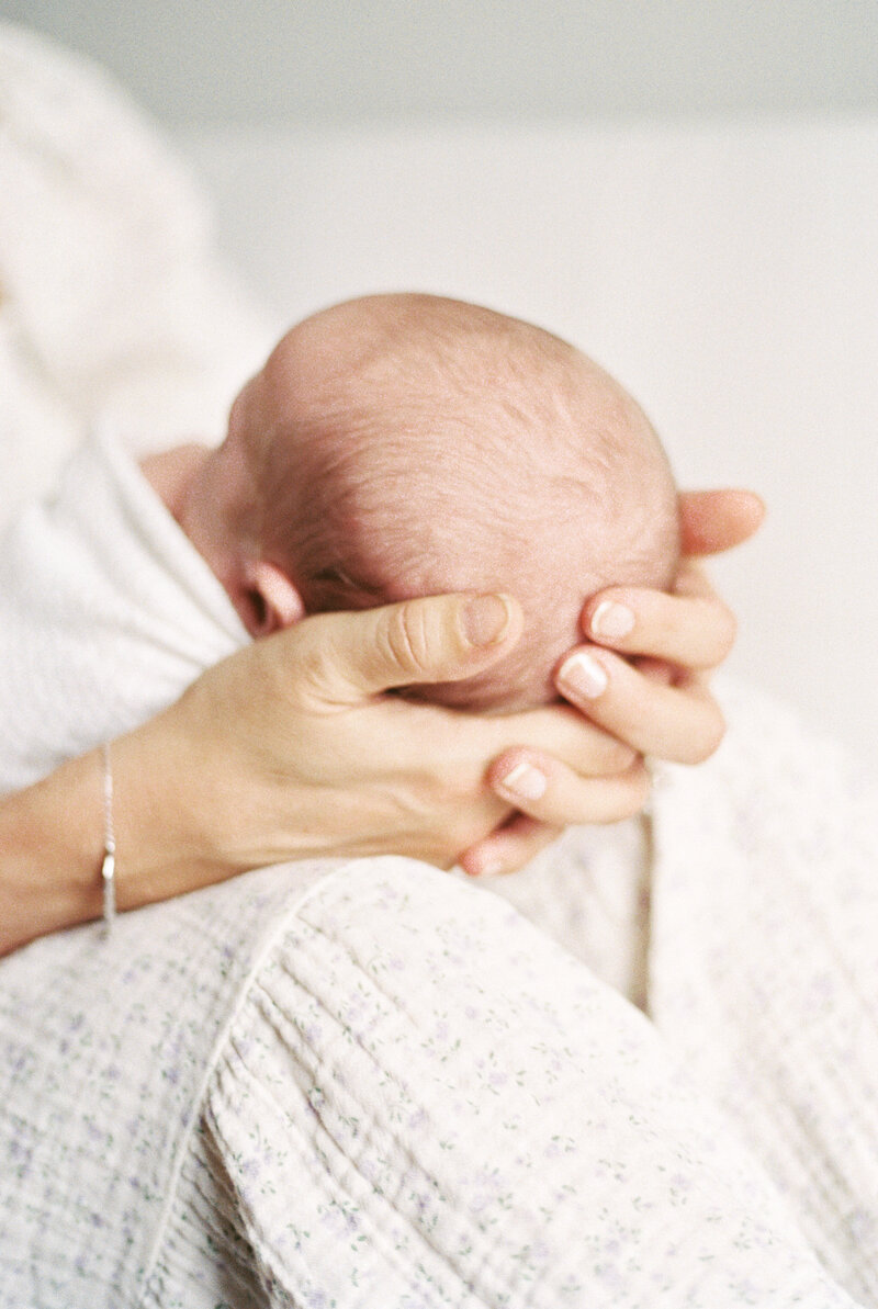 A sweet moment of a mom holding her newborn baby's head in her hands.