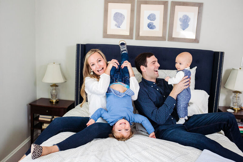 A family of four laughs goofily in a bedroom.