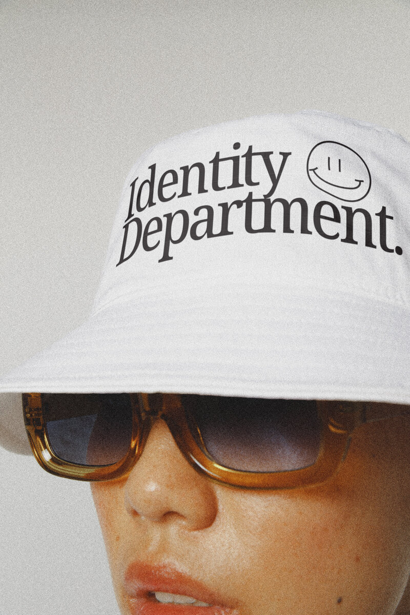 girl wearing a bucket hat that says Identity Department and sunglasses