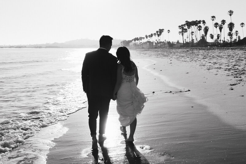 bride and groom take a walk on east beach in santa barbara near their wedding venue the cabrillo pavillion