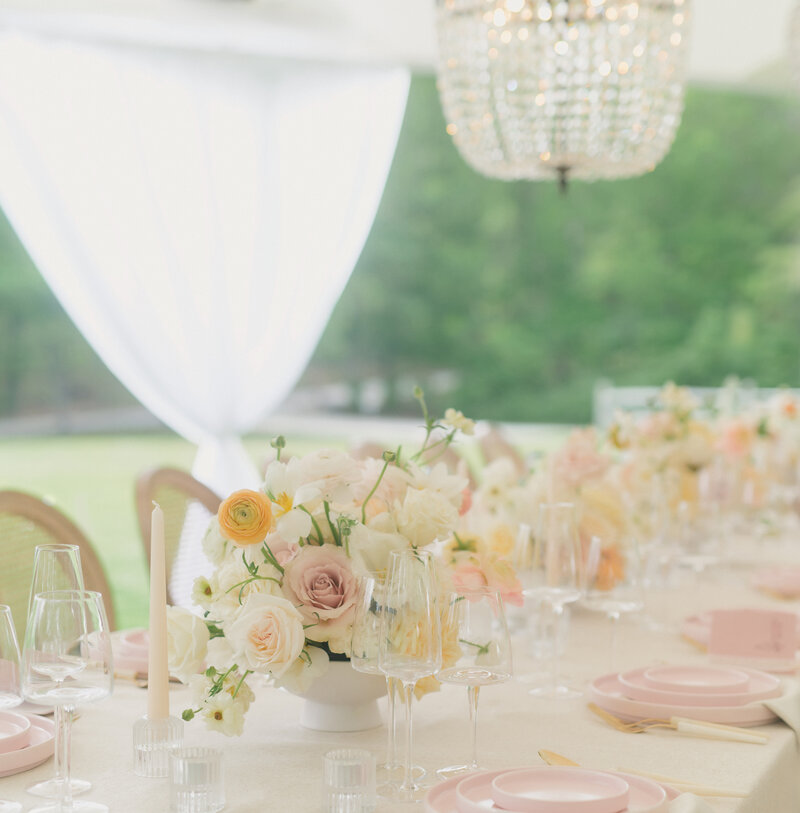 beautiful floral tablescape at summer tented wedding with chandelier and white and yellow flowers.