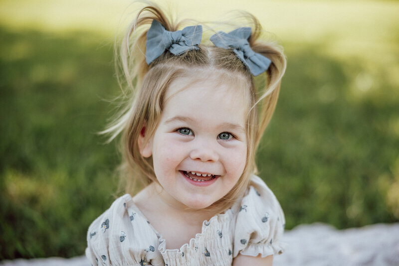 Close up portrait of a girl with pigtails smiling up at the camera. 