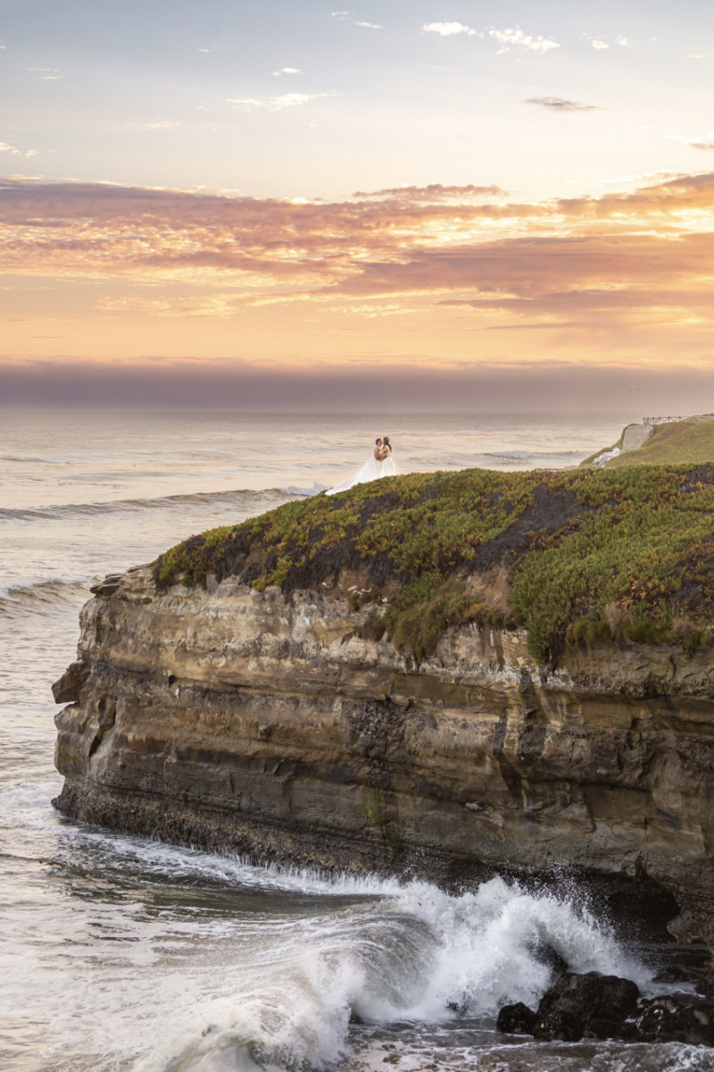 couple kiss and dip in front of white floral arch