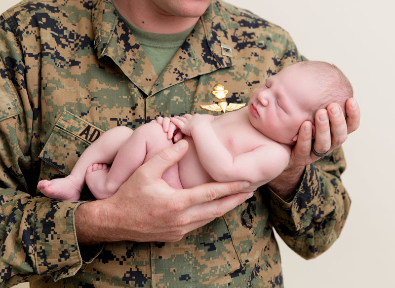 newborn boy in dads arms military uniform