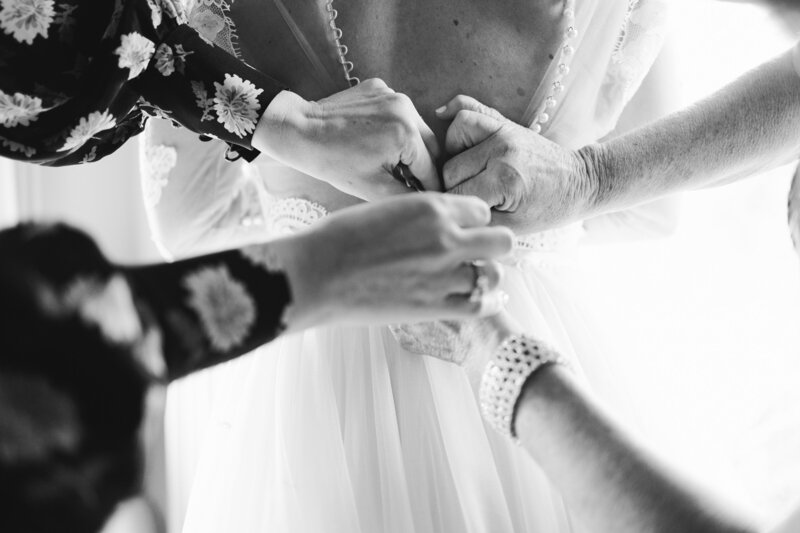 mom and maid of honour do up brides lace wedding dress