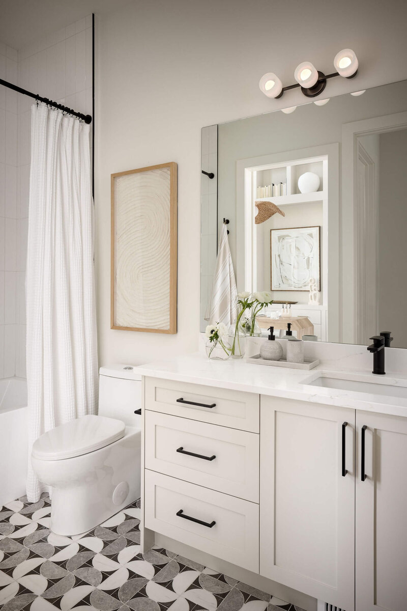 Inviting guest bathroom styled with warm neutral palettes, geometrical tile and black accents. 