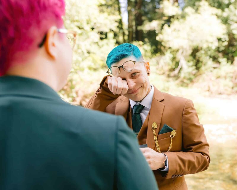 Lesbian wedding, both women wearing suits looking at each other during ceremony