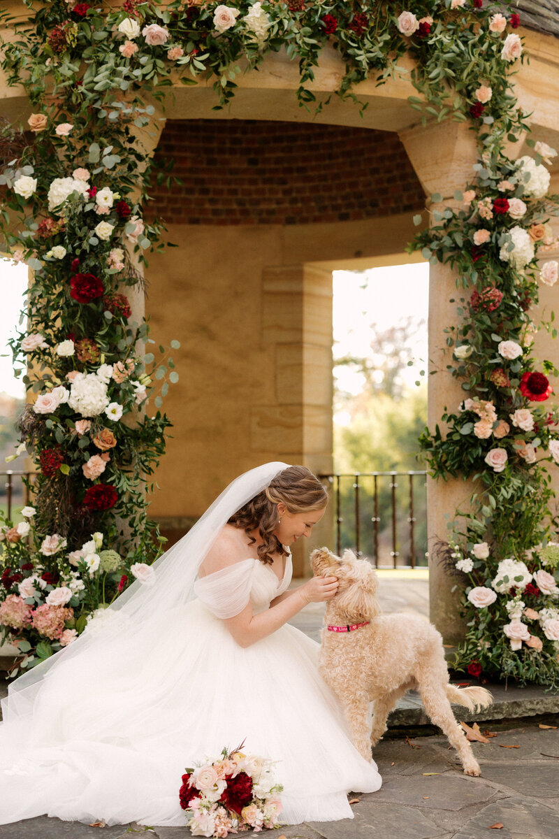 November wedding at Graylyn Estate, designed and planned by Charming Carolina — bride at the altar with her dog, surrounded by floral arrangements in the White Garden.