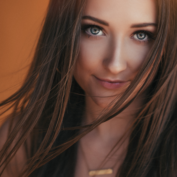 high school senior girl on orange backdrop studio senior portrait