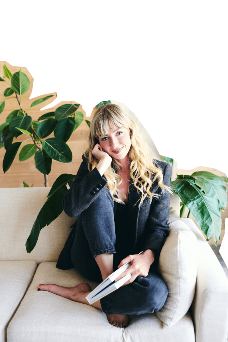 A woman sits on a couch with a book in hand, reflecting on her therapy journey and feelings of being stuck.