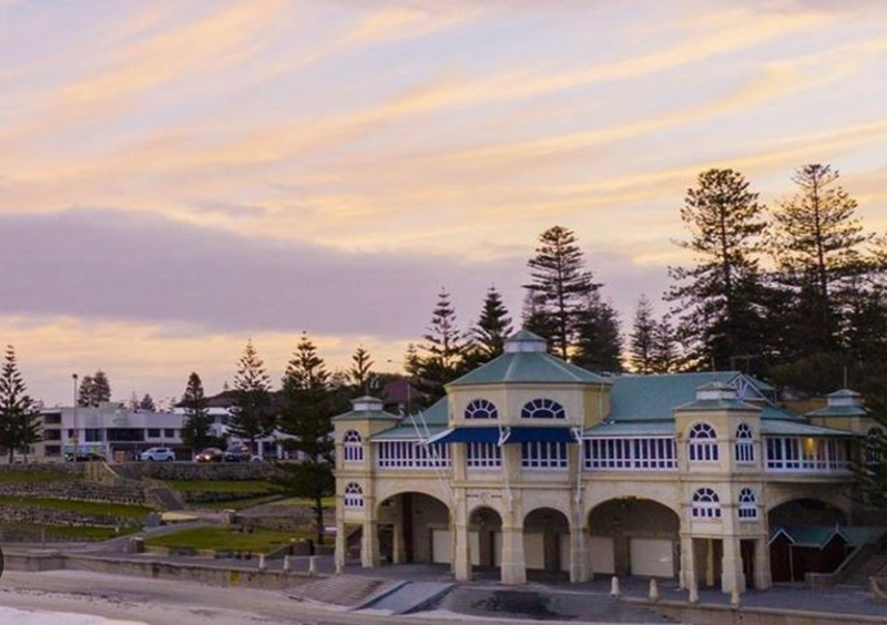A bride and groom cuddling in an outdoor area under the shade of a tree