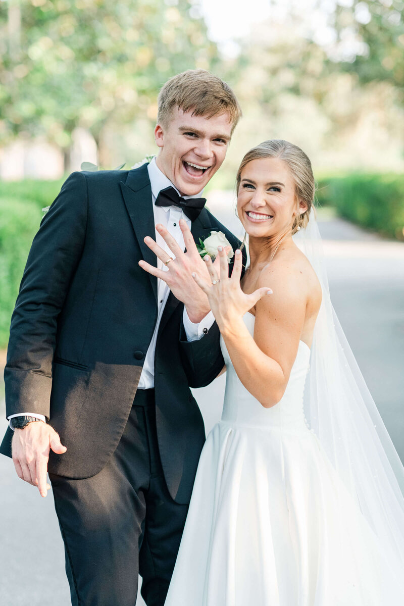 Bride and groom showing off their rings by pointing them directly at the camera during bridal portraits