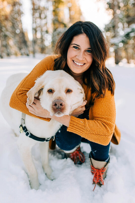 woman smiling with lab standing in snow in Breckenridge