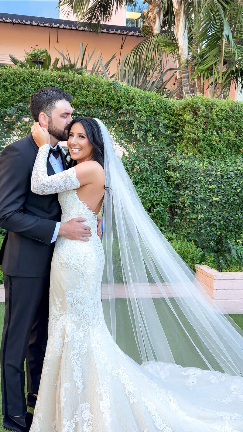 Groom kissing bride on the temple in the gardens of La Valencia Hotel in La Jolla, California.