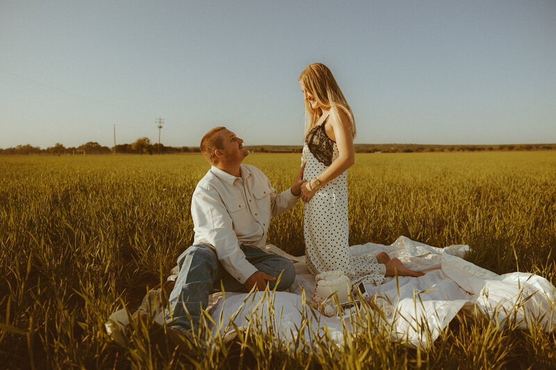 Intimate pregnancy announcement in a luscious green field in Ovalo, TX