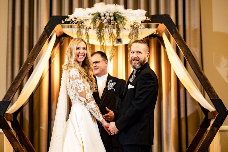 A wedding couple holds hands and looks at the crowd during their new years eve wedding at the Hancock Hotel in Findlay Ohio
