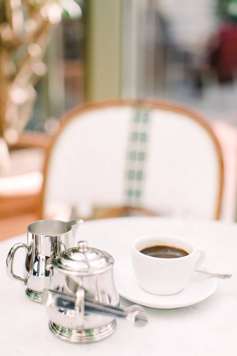 White French Bistro Chair With Silver Coffee Pot Creamer and Coffee Cup - Brenda Chadambura