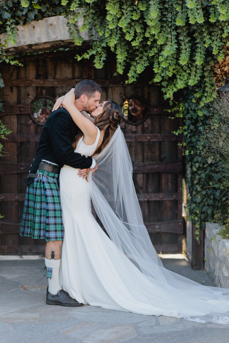 The perfect place for a destination wedding A Groom wears a kilt while he kisses a bride 