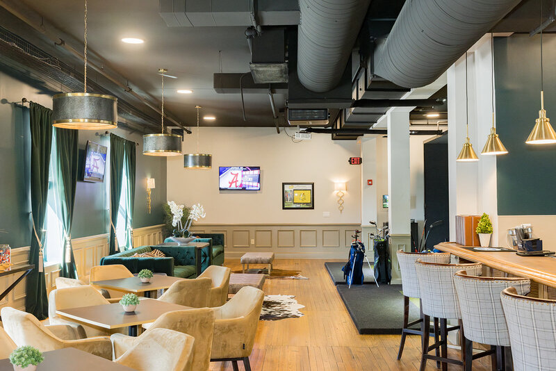 The Player's Club in Downtown Columbia, SC, is captured in this branding photograph, showcasing its sophisticated indoor golf and social lounge atmosphere. The warm lighting, plush seating, and golf simulators create an inviting space for both business professionals and golf enthusiasts. This image highlights the club’s elegant interior, making it an ideal location for networking, corporate events, and luxury entertainment in Columbia.