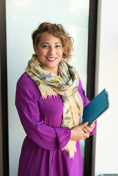 Woman with short hair, wearing a purple shirt and a scarf