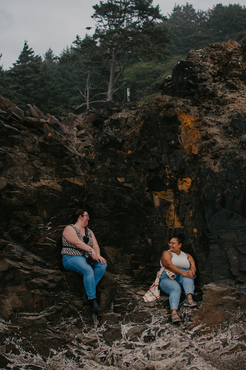 Katelin and Ashley sitting in a rock formation on the coast at Cannon Beach.