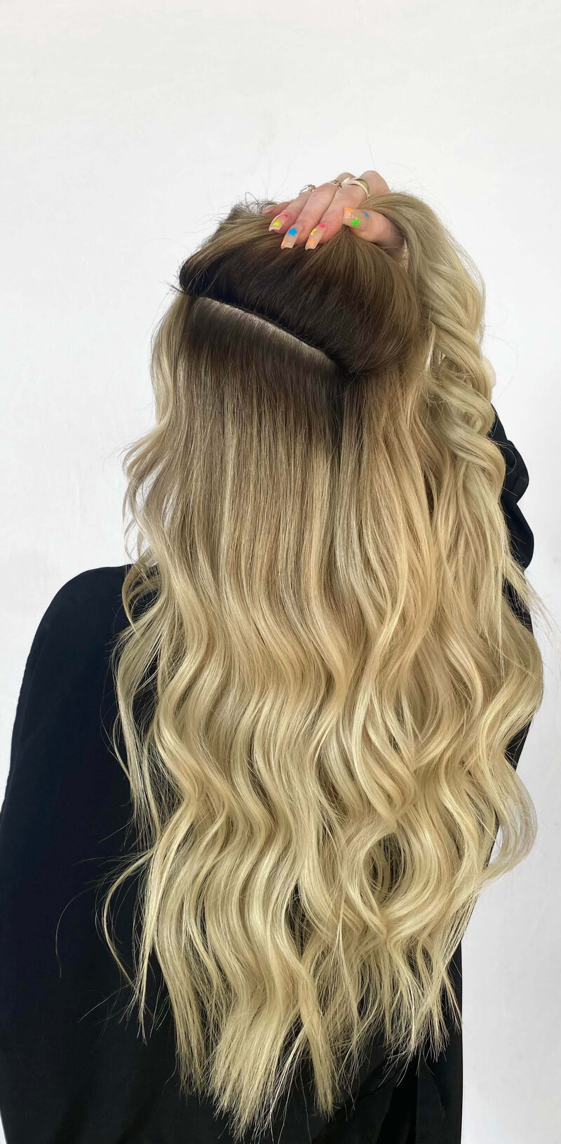 Back of woman's head showcasing blond blended hair extensions using IBE® method
