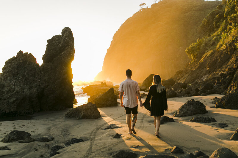 couple at beach walking into sunset
