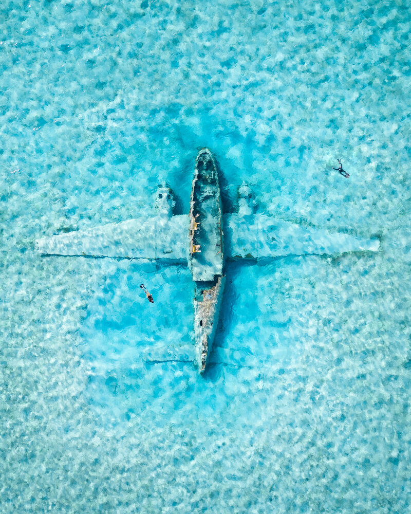 Plane underwater with two people swimming around
