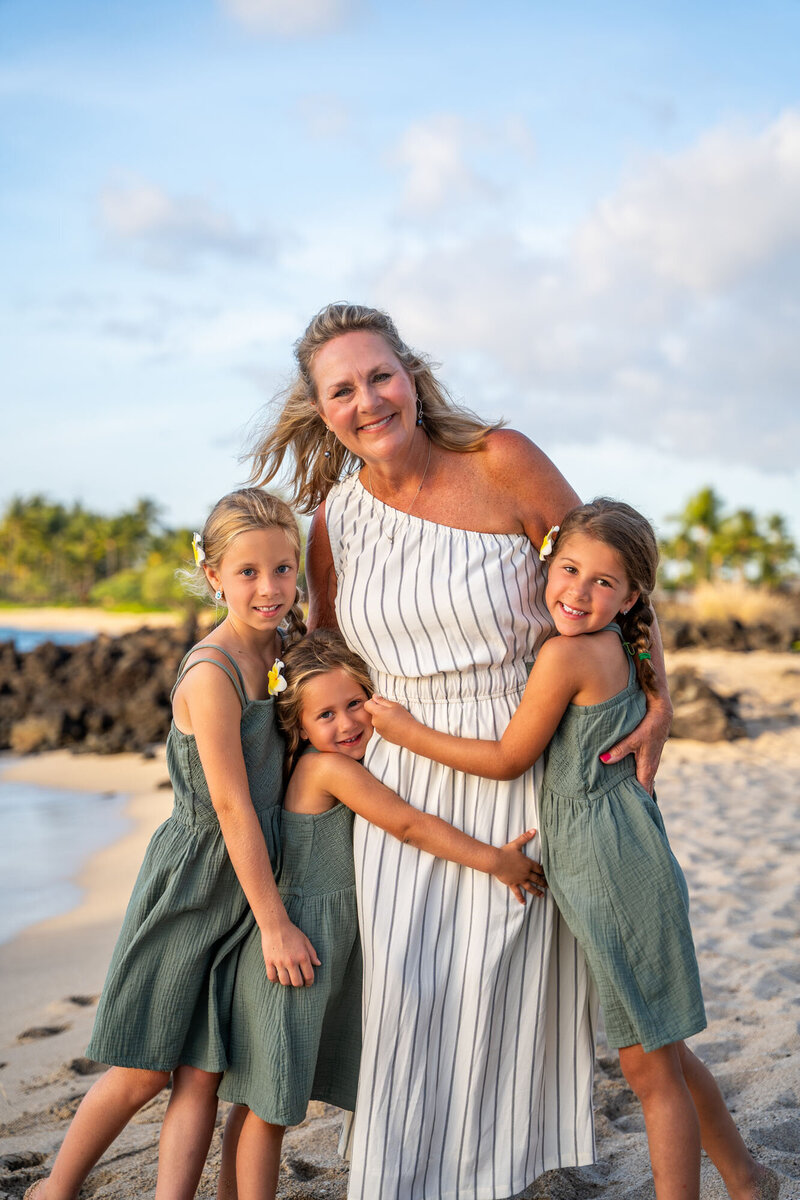 Mom holding her little girls on the beach taken by one of the best Big Island photographers