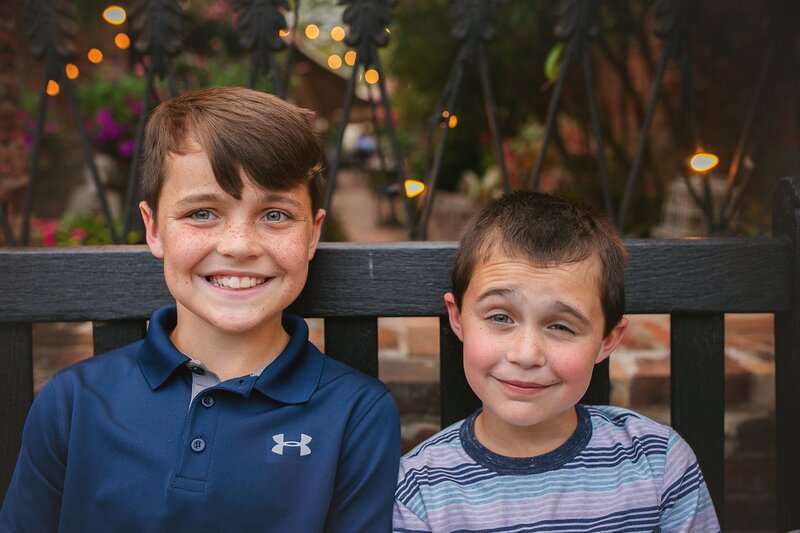 two-siblings-sharing-a-playful-moment-while-sitting-on-porch-steps-during-an-indianapolis-family-session