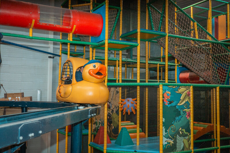 Kinderen spelen binnen in de overdekte speelkasteel van Sprookjeshof, met klimtoestellen, glijbanen en zachte speelmatten. 