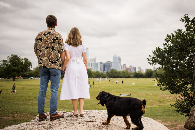 Man and woman holding each others hands with their dog behind