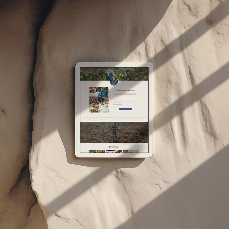 A tablet on a stone wall, representing the innovative spirit of Brave Nature School amidst a natural setting.
