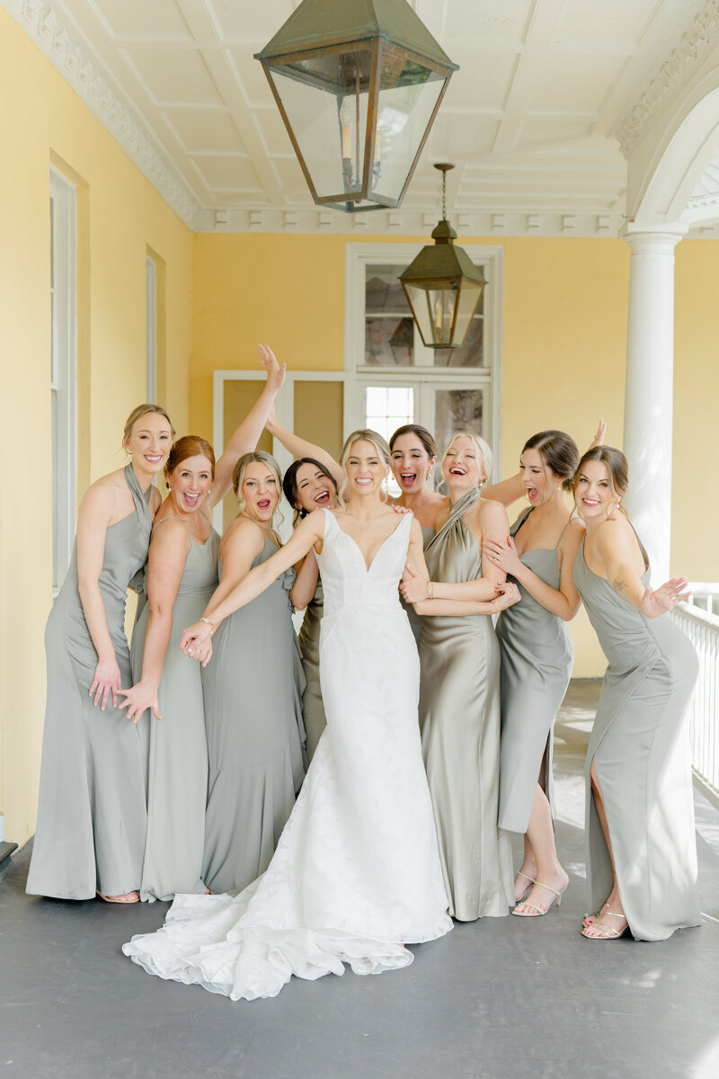 Bride candid photo with bridesmaids after first look. Bridesmaids in muted green dresses.