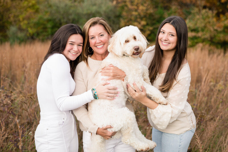 Mom and daughters holding labradoodle in a field for Northern Virginia family photos