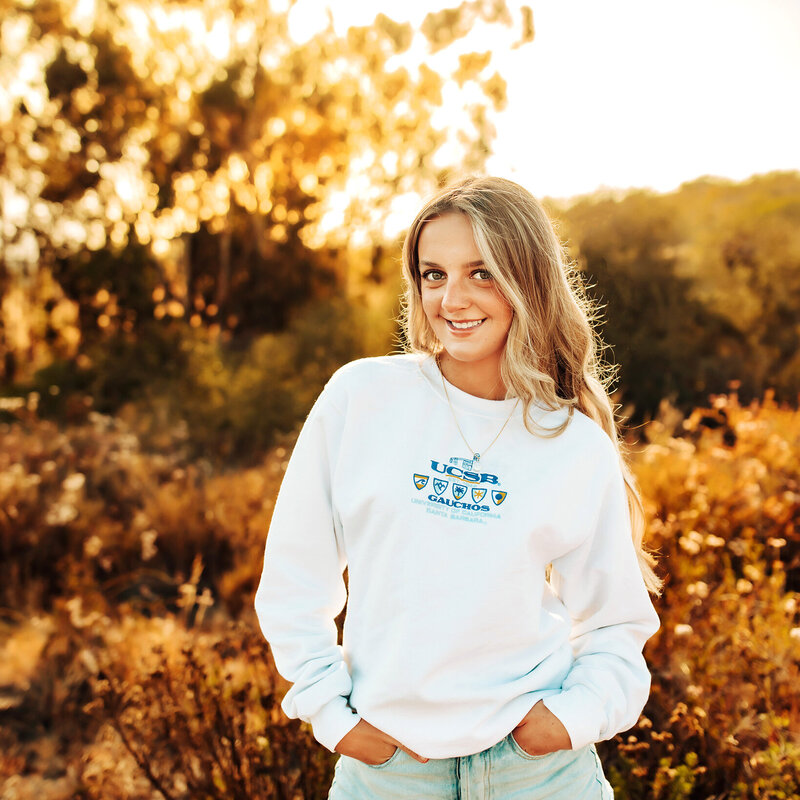 High school senior showcasing her college of choice in a sweatshirt at sunset.