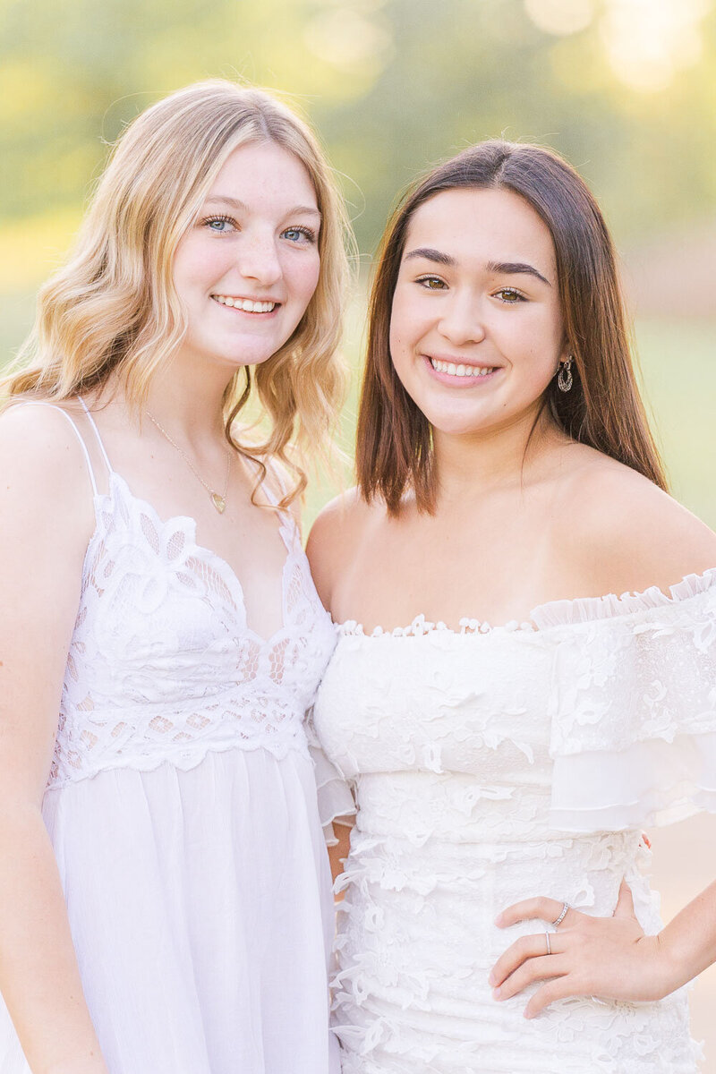 high school girls standing beside each other smiling for their senior pictures in Ashburn, VA