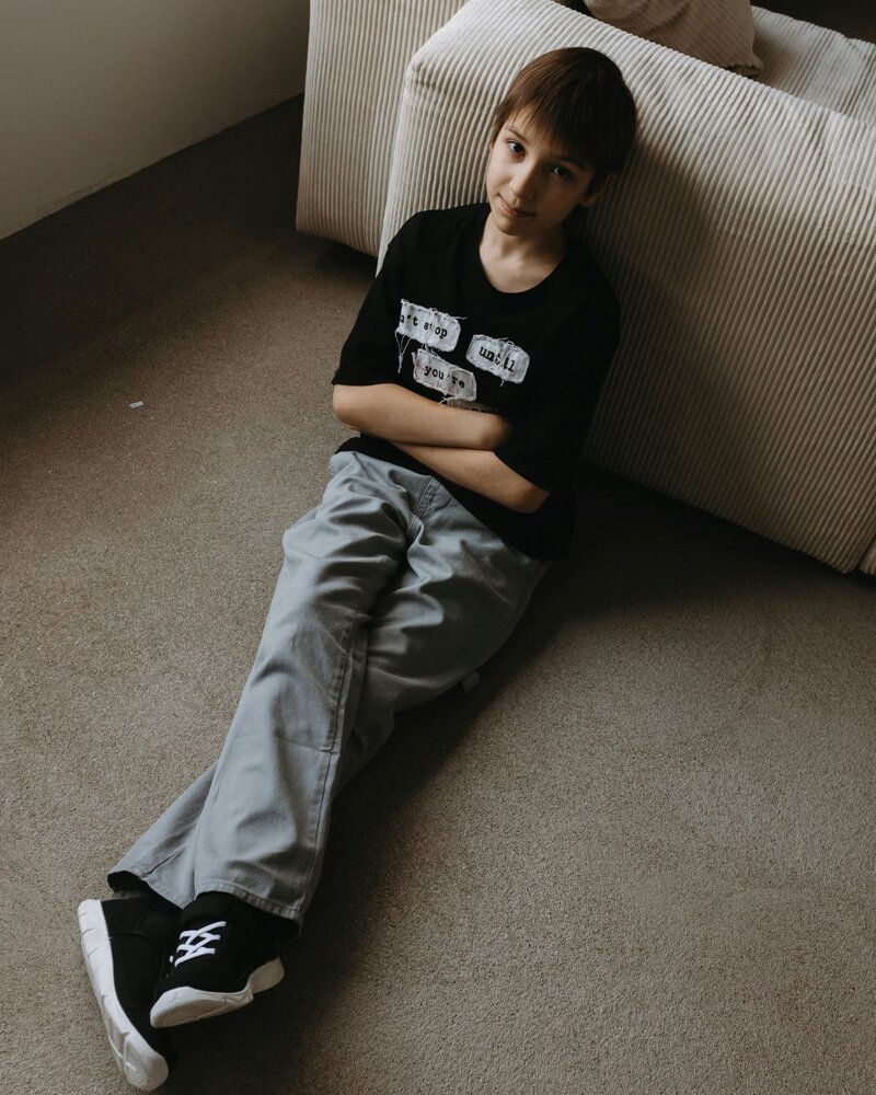 Man sitting in a green velvet chair with his head resting in his hand, conveying stress or contemplation.