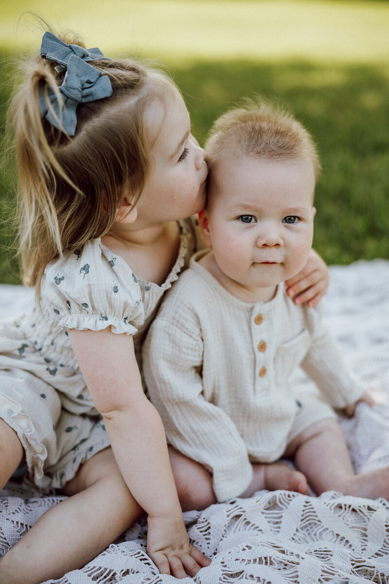 Toddler kissing brother's temple with brother looking at camera during an extended family session in Farmington, Missouri. 