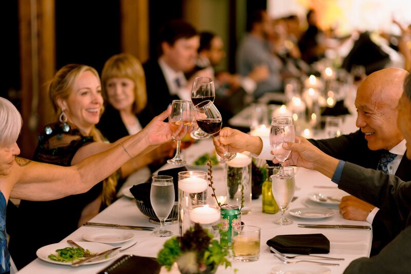 Guests at a formal event engaging in a toast with wine glasses.
